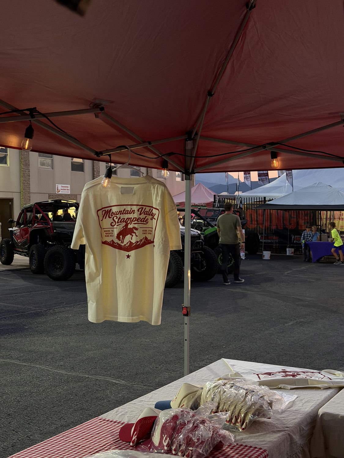 Mountain Valley Stampede tee hanging in the booth tent at dusk