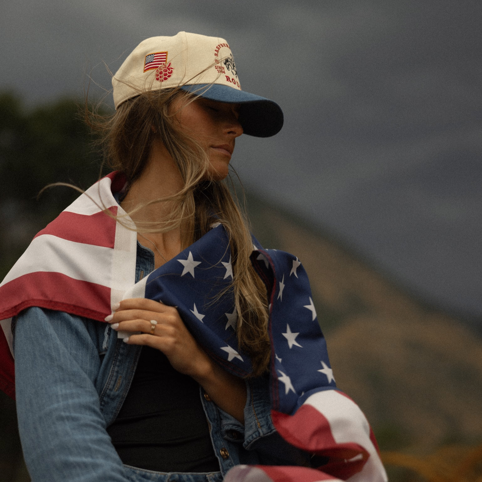 Model in custom Raspberry Days Rodeo cap draped in American flag