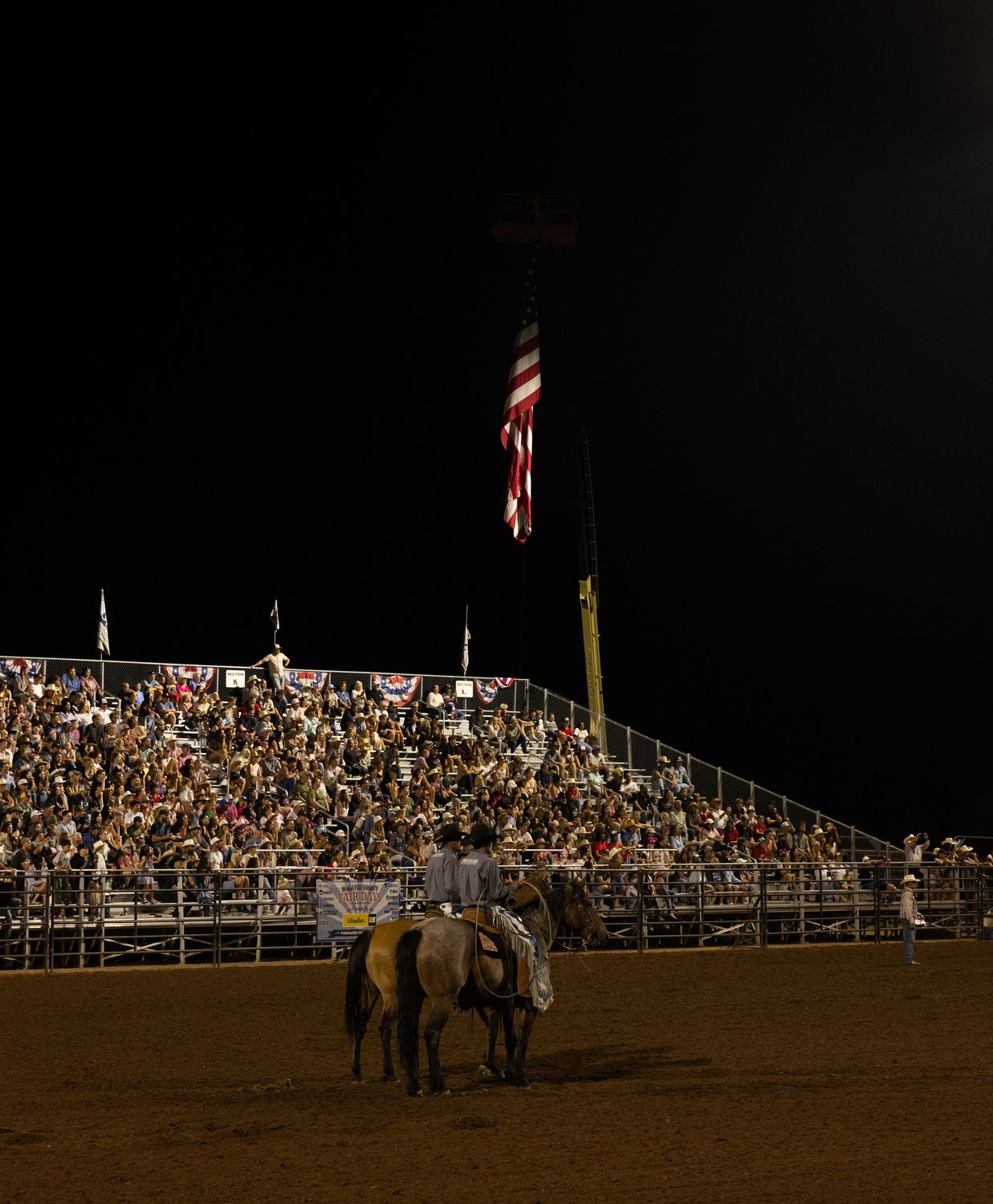 Packed grandstand at night with the flag rider circling the arena