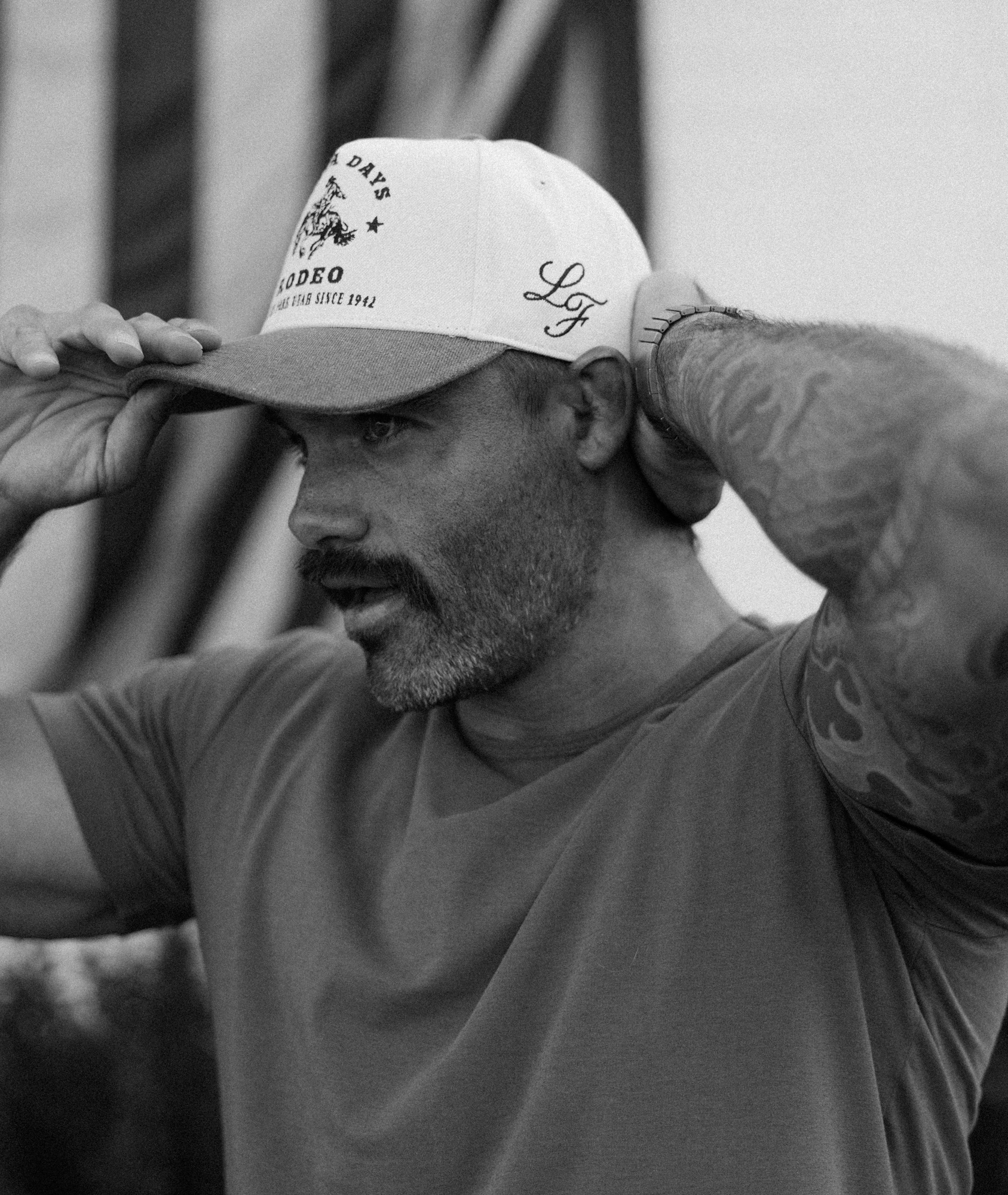 Black and white close-up of a man adjusting a custom Loud Face cap