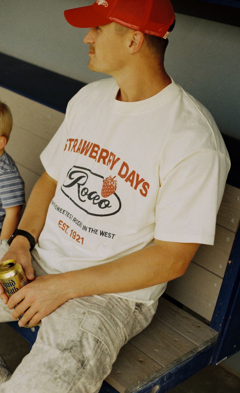 Fan in the bleachers wearing a cream Strawberry Days Rodeo tee