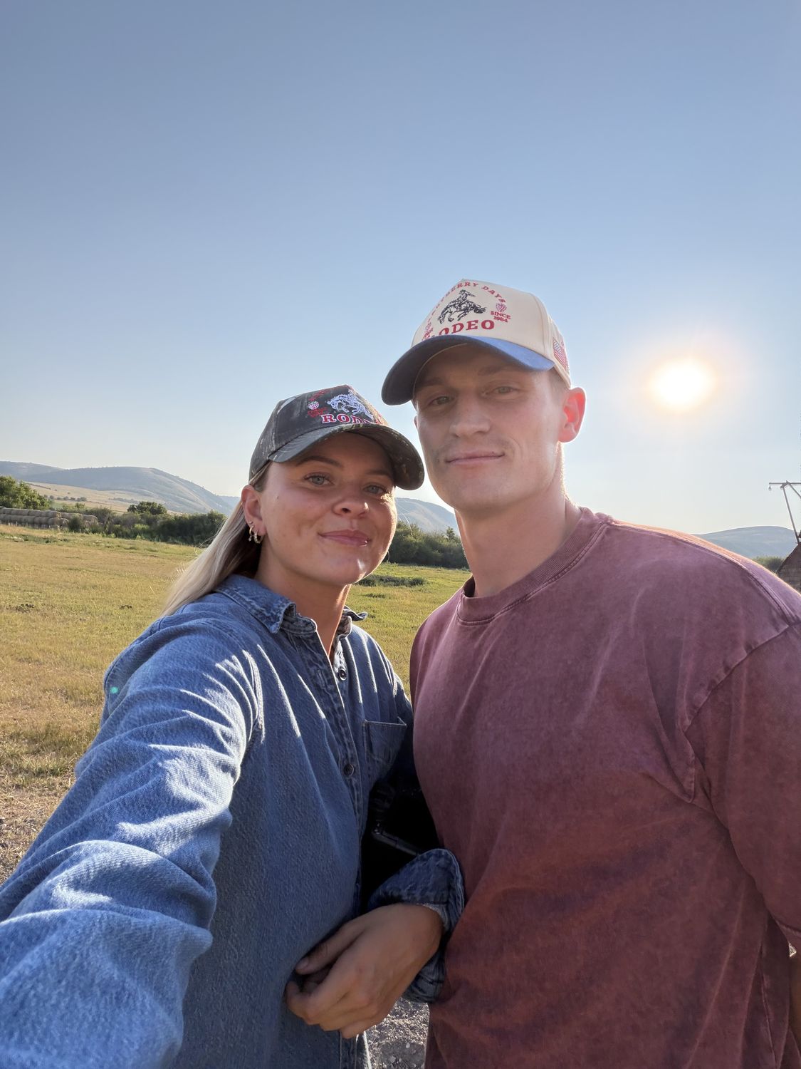 Couple at golden hour in Strawberry Days Rodeo and camo rodeo trucker hats