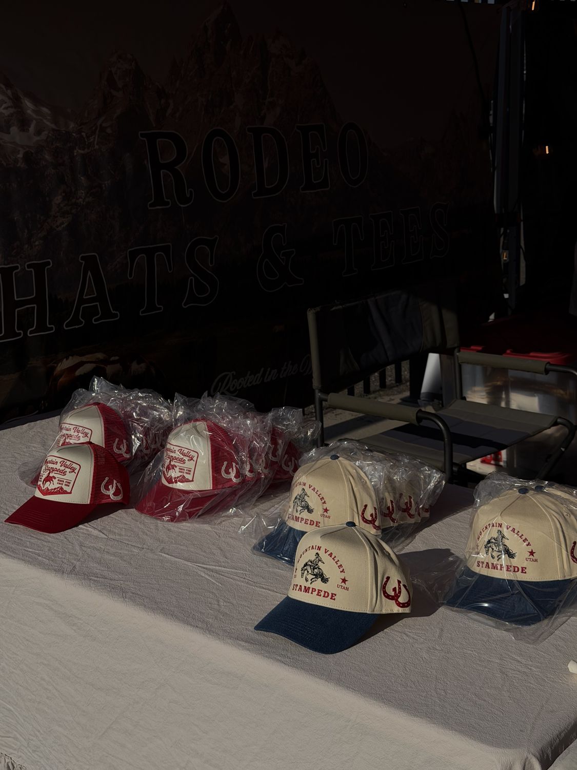 Mountain Valley Stampede trucker hats bagged and laid out under the Rodeo Hats & Tees banner