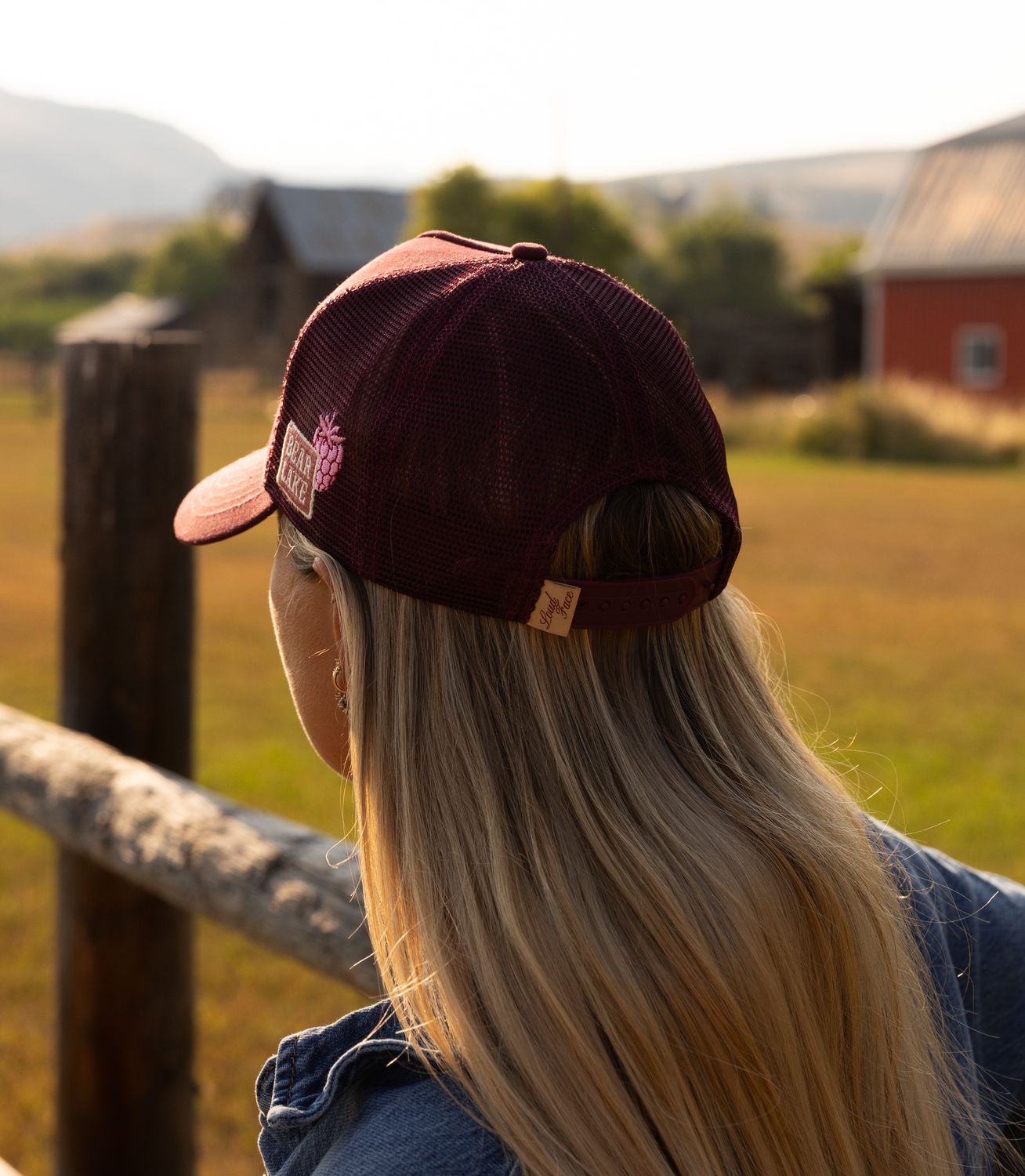 Back view of a maroon Bear Lake Raspberry Days cap at a fence rail