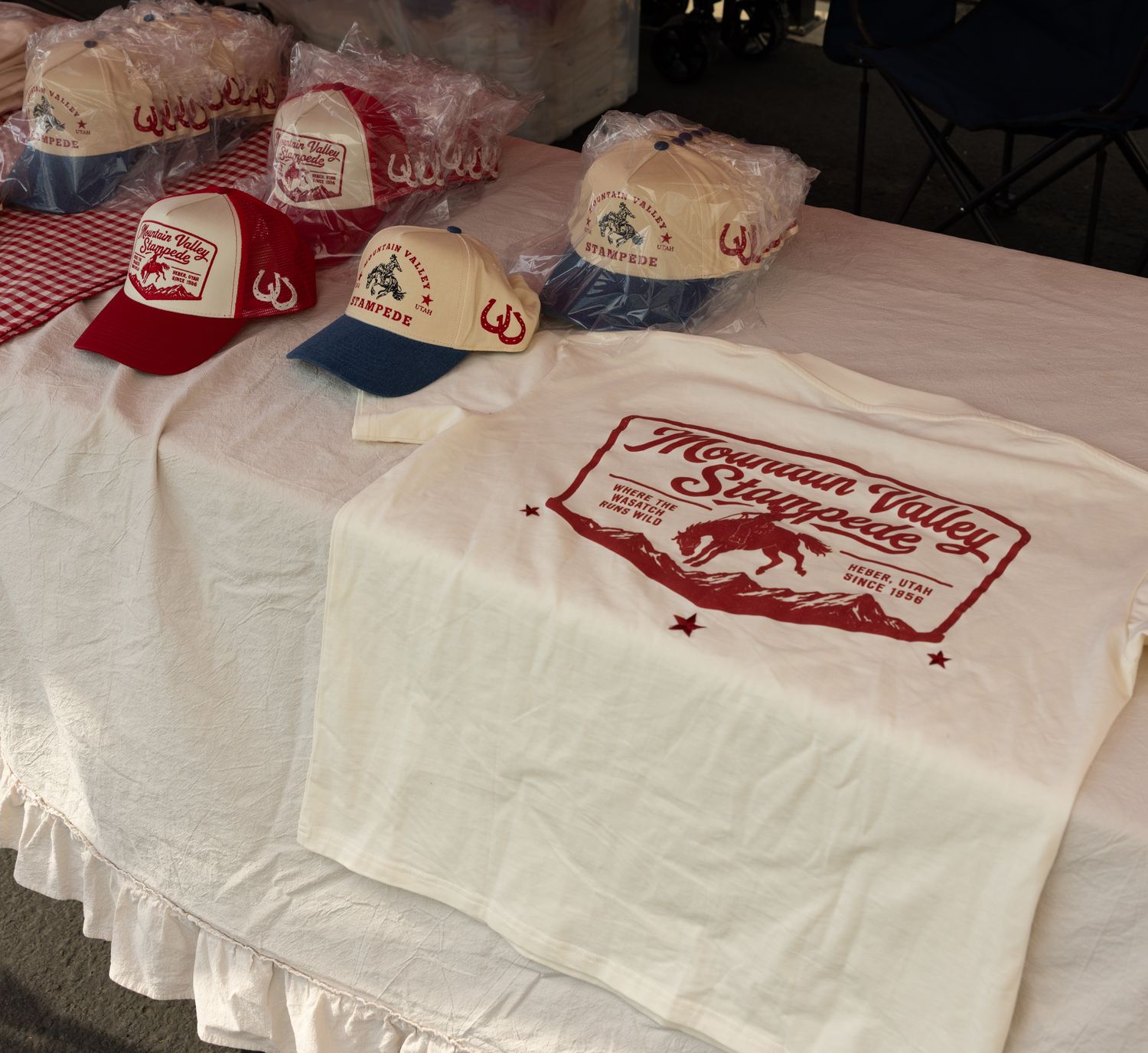 Mountain Valley Stampede caps and tee laid out on the booth table