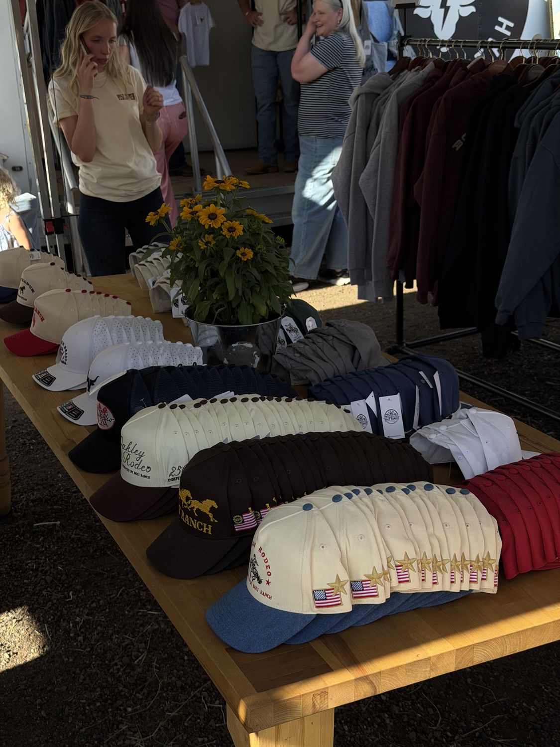 Rows of Bolt Ranch and Oakley Rodeo caps laid out across the wood booth table