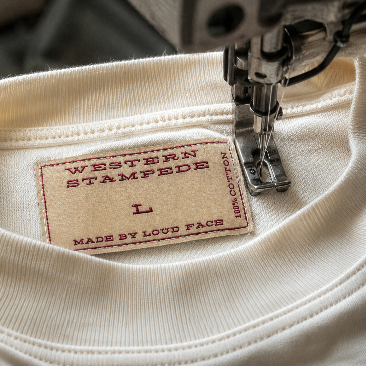 Close-up of a woven shirt label being sewn into a cream garment